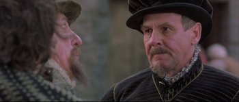 Movie still from “Shakespeare in Love” (1998), directed by John Madden – A man with a beard and a hat is talking to another man with a beard; Close Up shot, Over the shoulder angle