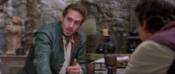 Movie still from “Shakespeare in Love” (1998), directed by John Madden – A man sitting at a table in front of a candle; Close Up shot, Over the shoulder angle