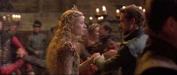 Movie still from “Shakespeare in Love” (1998), directed by John Madden – A man and a woman holding hands in front of a crowd of onlookers; Medium shot, Over the shoulder angle