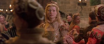 Movie still from “Shakespeare in Love” (1998), directed by John Madden – A woman wearing a gold dress and a crown; Medium shot, Over the shoulder angle