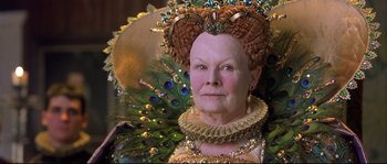 Movie still from “Shakespeare in Love” (1998), directed by John Madden – An older woman wearing a peacock feather headdress; Close Up shot, Over the shoulder angle