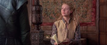 Movie still from “Shakespeare in Love” (1998), directed by John Madden – A young woman holding an open book while standing in front of an ornate statue; Medium shot, Low angle