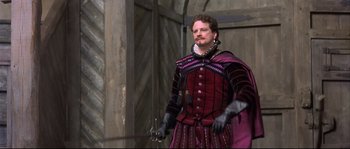 Movie still from “Shakespeare in Love” (1998), directed by John Madden – A man dressed in medieval garb holding a sword; Medium shot, Over the shoulder angle