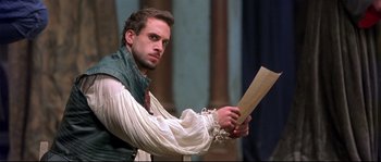 Movie still from “Shakespeare in Love” (1998), directed by John Madden – A man holding a piece of wood while standing on a stage; Close Up shot, Over the shoulder angle