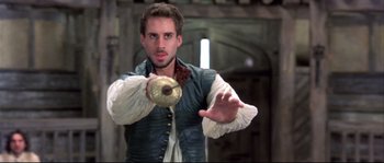 Movie still from “Shakespeare in Love” (1998), directed by John Madden – A man in medieval garb holding a metal object; Close Up shot, Over the shoulder angle