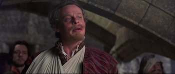 Movie still from “Shakespeare in Love” (1998), directed by John Madden – A man with long hair and a beard is wearing a red robe; Close Up shot, Low angle