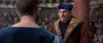 Movie still from “Shakespeare in Love” (1998), directed by John Madden – A man wearing a blue hat and a gold and blue outfit; Medium shot, Over the shoulder angle