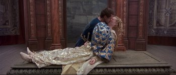 Movie still from “Shakespeare in Love” (1998), directed by John Madden – A man and a woman dressed in medieval garb kissing; Wide shot, High angle