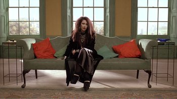 Movie still from “Shallow Grave” (1994), directed by Danny Boyle – A woman sitting on top of a couch in front of a window; Wide shot, Low angle