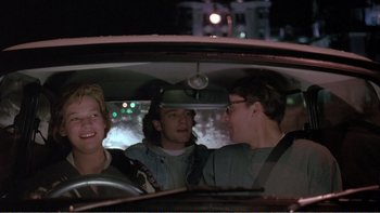 Movie still from “Shallow Grave” (1994), directed by Danny Boyle – Three young men in the back seat of a car at night; Medium shot, Low angle