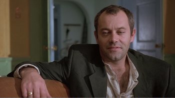 Movie still from “Shallow Grave” (1994), directed by Danny Boyle – A person wearing a suit and tie; Close Up shot, Low angle