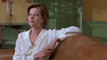 Movie still from “Shallow Grave” (1994), directed by Danny Boyle – A woman sitting on top of a couch in a living room; Medium shot, Low angle