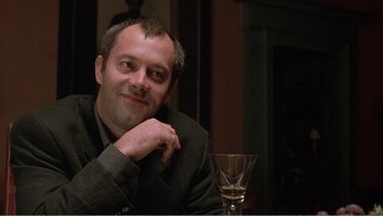 Movie still from “Shallow Grave” (1994), directed by Danny Boyle – A man sitting in front of a wine glass; Close Up shot, Over the shoulder angle