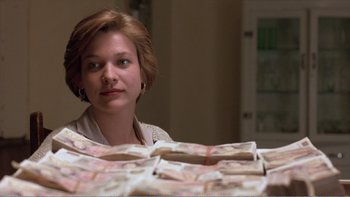 Movie still from “Shallow Grave” (1994), directed by Danny Boyle – A woman sitting in front of a pile of money; Close Up shot, Low angle