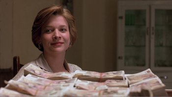 Movie still from “Shallow Grave” (1994), directed by Danny Boyle – A woman sitting in front of a pile of money; Medium shot, Low angle