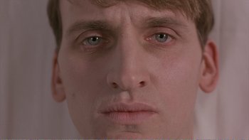 Movie still from “Shallow Grave” (1994), directed by Danny Boyle – A man's face with blue eyes; Extreme Close Up shot, Low angle