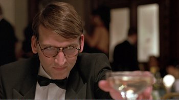 Movie still from “Shallow Grave” (1994), directed by Danny Boyle – A man in a tuxedo holding a glass of wine; Close Up shot, Low angle