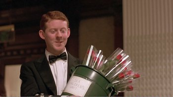Movie still from “Shallow Grave” (1994), directed by Danny Boyle – A man in a suit and bow tie holding a bucket of drinks; Close Up shot, High angle