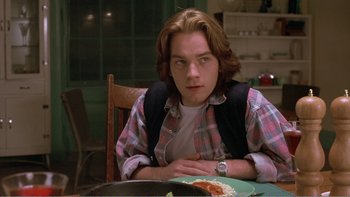 Movie still from “Shallow Grave” (1994), directed by Danny Boyle – A man sitting at a table with a plate of food; Close Up shot, Over the shoulder angle
