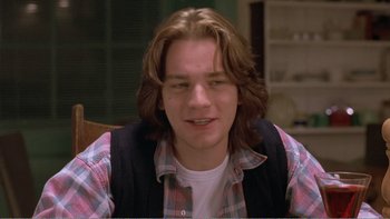 Movie still from “Shallow Grave” (1994), directed by Danny Boyle – A man with long brown hair wearing a plaid shirt; Close Up shot, Over the shoulder angle