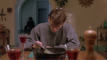 Movie still from “Shallow Grave” (1994), directed by Danny Boyle – A man sitting at a table with a bowl of food; Medium shot, Over the shoulder angle