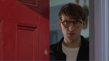 Movie still from “Shallow Grave” (1994), directed by Danny Boyle – A man with glasses standing in front of a red door; Close Up shot, Over the shoulder angle
