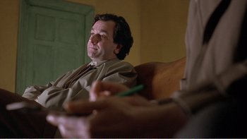 Movie still from “Shallow Grave” (1994), directed by Danny Boyle – A man sitting in a chair while holding a pen; Close Up shot, Over the shoulder angle