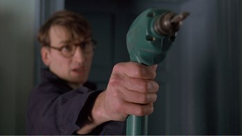 Movie still from “Shallow Grave” (1994), directed by Danny Boyle – A man holding a green drill in his hand; Close Up shot, Low angle