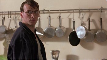 Movie still from “Shallow Grave” (1994), directed by Danny Boyle – A man standing in front of a wall of pots and pans in a kitchen; Close Up shot, Over the shoulder angle
