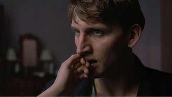 Movie still from “Shallow Grave” (1994), directed by Danny Boyle – A person with his hand to his face; Close Up shot, Over the shoulder angle