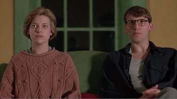 Movie still from “Shallow Grave” (1994), directed by Danny Boyle – A man and a woman sitting next to each other on a couch; Medium shot, Low angle