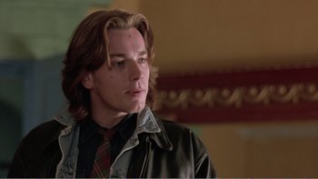 Movie still from “Shallow Grave” (1994), directed by Danny Boyle – A man with long brown hair wearing a leather jacket; Close Up shot, Low angle