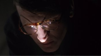 Movie still from “Shallow Grave” (1994), directed by Danny Boyle – A man wearing glasses looking into the camera; Close Up shot, Low angle
