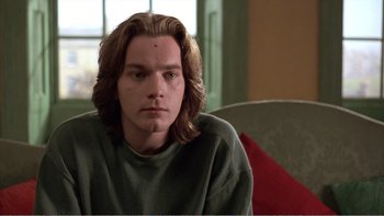 Movie still from “Shallow Grave” (1994), directed by Danny Boyle – A man with long hair sitting in a chair; Close Up shot, Low angle