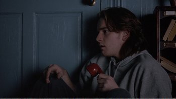 Movie still from “Shallow Grave” (1994), directed by Danny Boyle – A young man holding a tomato in his hand; Close Up shot, Over the shoulder angle