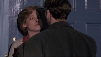 Movie still from “Shallow Grave” (1994), directed by Danny Boyle – A man and a woman looking into each other's eyes in front of a blue door; Close Up shot, Over the shoulder angle