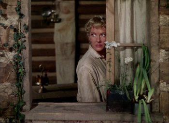 Movie still from “Shane” (1953), directed by George Stevens – A woman looking into a mirror in a log cabin; Medium shot, Low angle