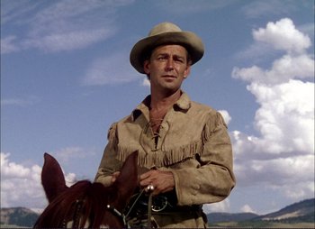 Movie still from “Shane” (1953), directed by George Stevens – A man wearing a cowboy hat standing next to a horse; Medium shot, Low angle