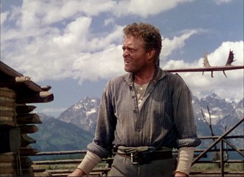 Movie still from “Shane” (1953), directed by George Stevens – A man standing on top of a hill near a mountain range; Medium shot, Low angle