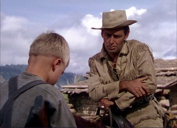 Movie still from “Shane” (1953), directed by George Stevens – A man wearing a hat and a jacket talking to a young boy; Medium shot, Over the shoulder angle