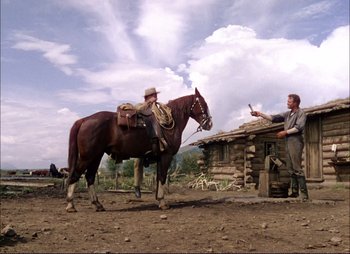Movie still from “Shane” (1953), directed by George Stevens – A man on a horse in front of a log cabin; Wide shot, Low angle