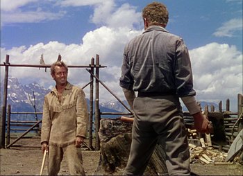 Movie still from “Shane” (1953), directed by George Stevens – Two men standing next to a pile of wood; Medium shot, Low angle