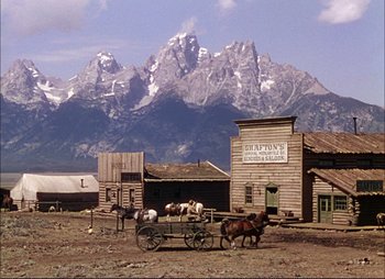 Movie still from “Shane” (1953), directed by George Stevens – A horse drawn carriage in front of a mountain range; Extreme Wide shot, Low angle