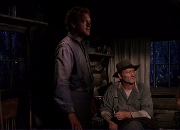 Movie still from “Shane” (1953), directed by George Stevens – Two men sitting on a chair in front of a fireplace; Medium shot, Low angle