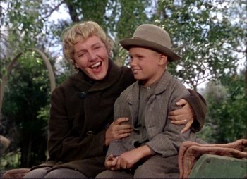 Movie still from “Shane” (1953), directed by George Stevens – An older woman sitting next to a young boy; Medium shot, Low angle