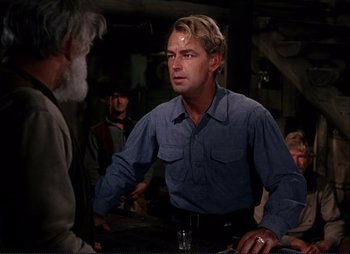 Movie still from “Shane” (1953), directed by George Stevens – A man in blue shirt talking to another man; Medium shot, Over the shoulder angle