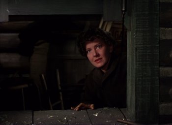 Movie still from “Shane” (1953), directed by George Stevens – A woman sitting at a table looking at the camera; Medium shot, Low angle