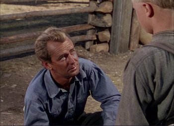 Movie still from “Shane” (1953), directed by George Stevens – A man sitting on the ground talking to another man; Close Up shot, Over the shoulder angle