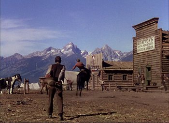 Movie still from “Shane” (1953), directed by George Stevens – A man riding a horse on top of a dirt field; Extreme Wide shot, Low angle