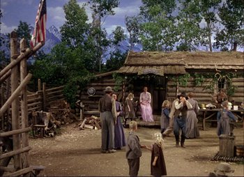 Movie still from “Shane” (1953), directed by George Stevens – A group of people standing in front of a log cabin; Wide shot, Low angle